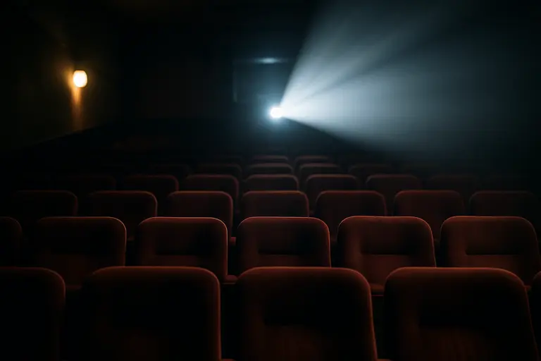 Movie theater seats facing a projection beam in an empty auditorium